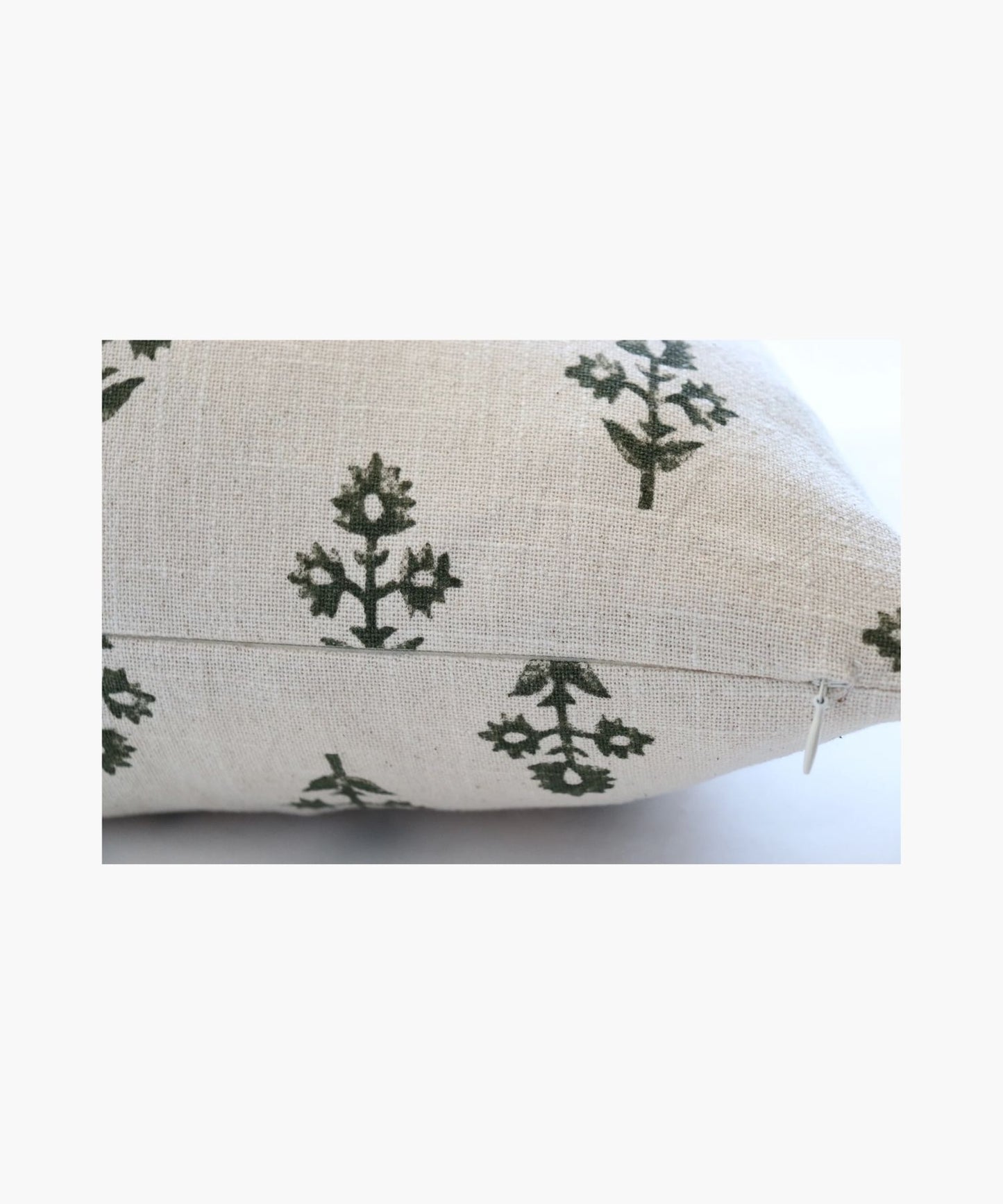 A detailed picture of beige pillow highlighting its color and pattern of evenly spaced, small dark green botanicals. The design is simple and calming, evoking a natural, serene atmosphere.