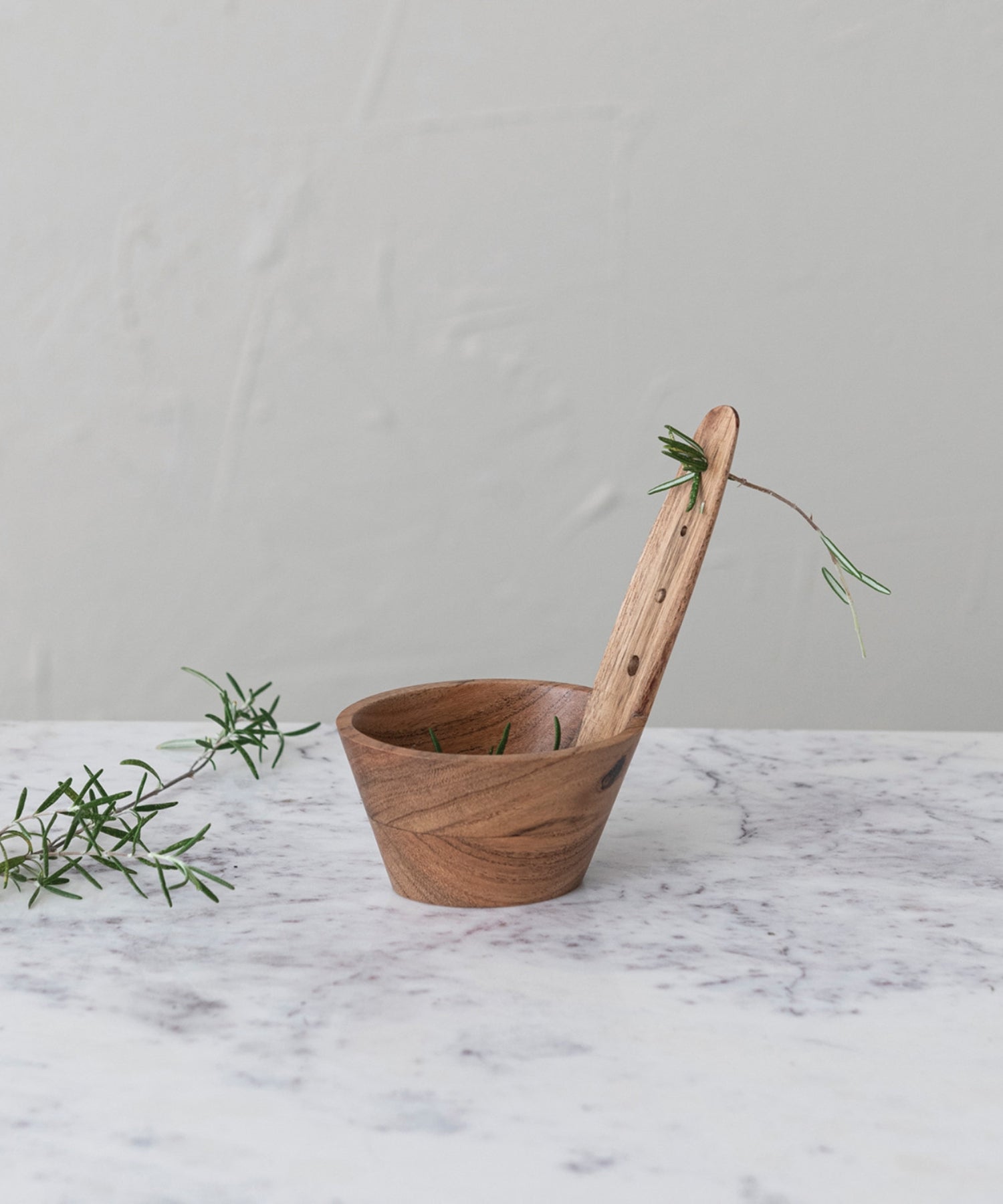 A natural Acacia wood herb stripper featuring a cylindrical bowl and a paddle-like handle with holes. The wood grain is prominent, conveying a rustic, hand-crafted feel.