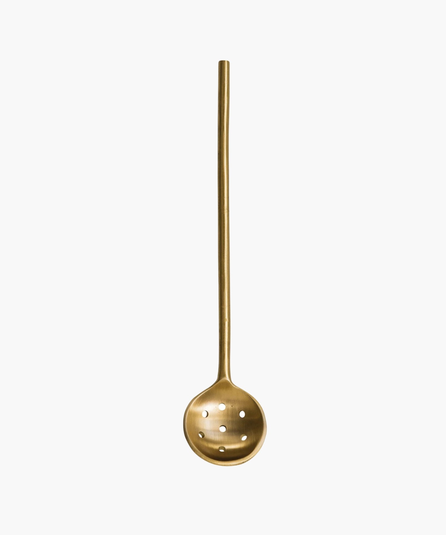 A minimalist brass slotted spoon with a long handle and round, perforated ladle, evoking elegance and simplicity.