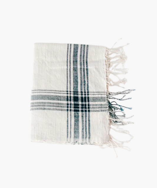 A neatly folded blue and white striped hand towel with fringe edges. The soft texture and earthy tones convey warmth and comfort.