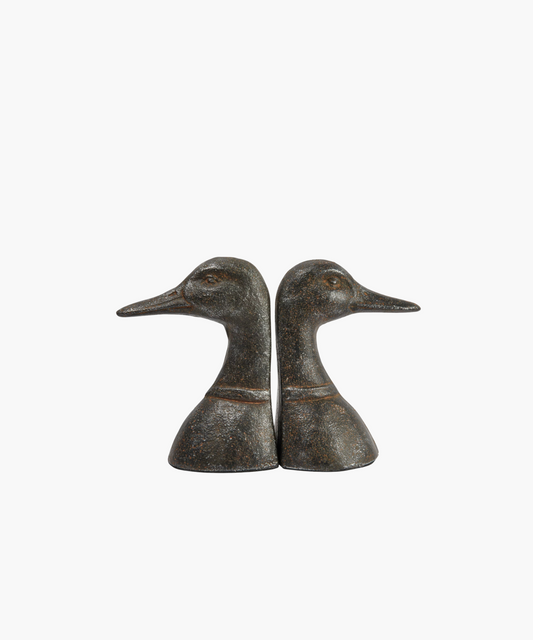 Two bronze duck busts facing opposite directions with detailed textures, set against a white background. Symmetrical and rustic, conveying elegance.