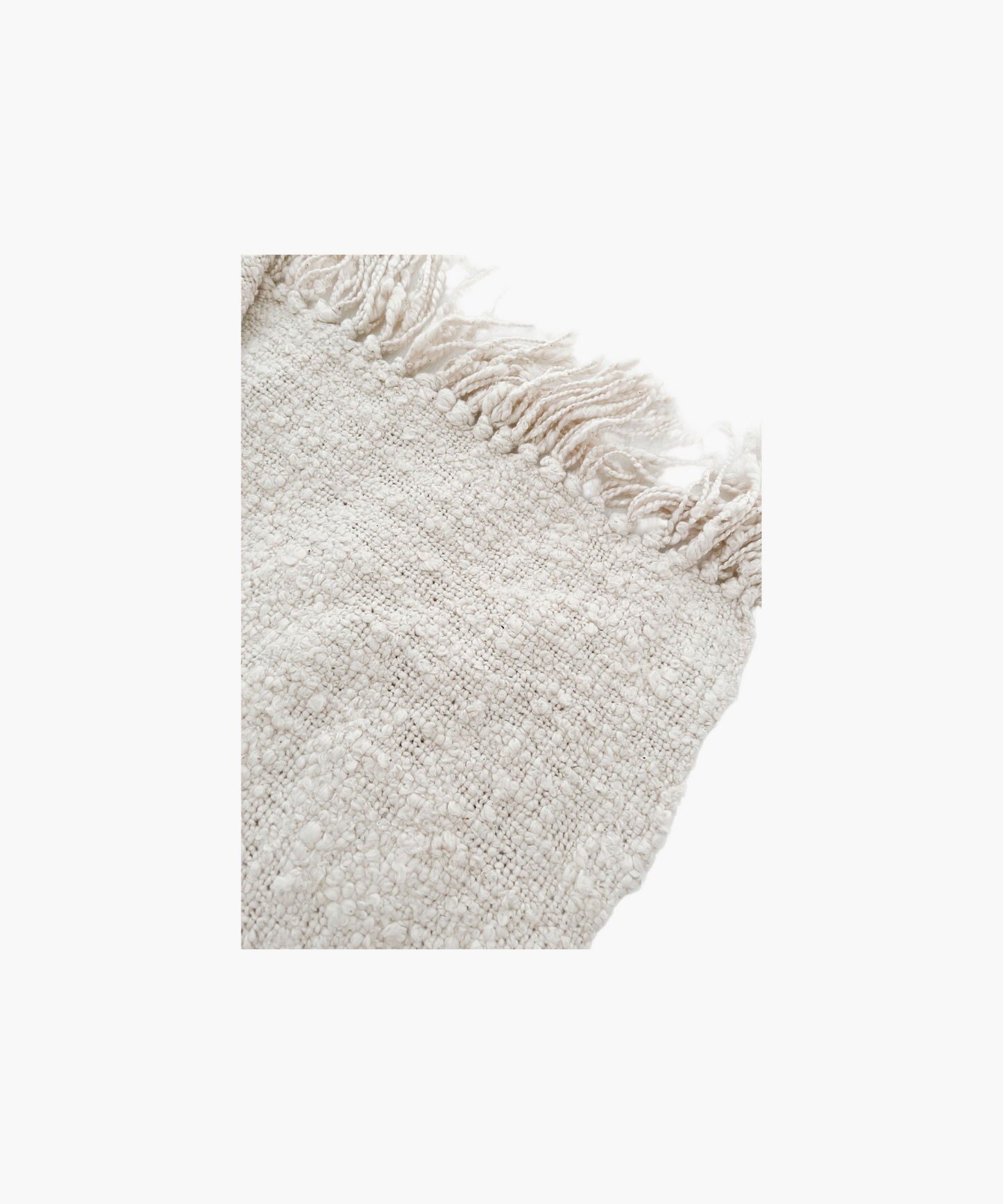 A soft, ivory colored woven throw blanket with a textured pattern and fringed edges, conveying a cozy and inviting feel. 