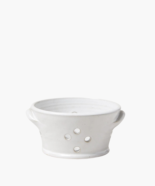 White ceramic colander with two side handles and five round drainage holes. The smooth, minimalist design conveys a clean and simple aesthetic.