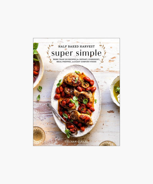 Cookbook cover titled "Half Baked Harvest: Super Simple" by Tieghan Gerard, featuring a plate of roasted chicken with cherry tomatoes and herbs on a rustic table.