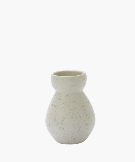 A round, textured beige vase with a speckled pattern on a white background. The simple design conveys an earthy and minimalist aesthetic.