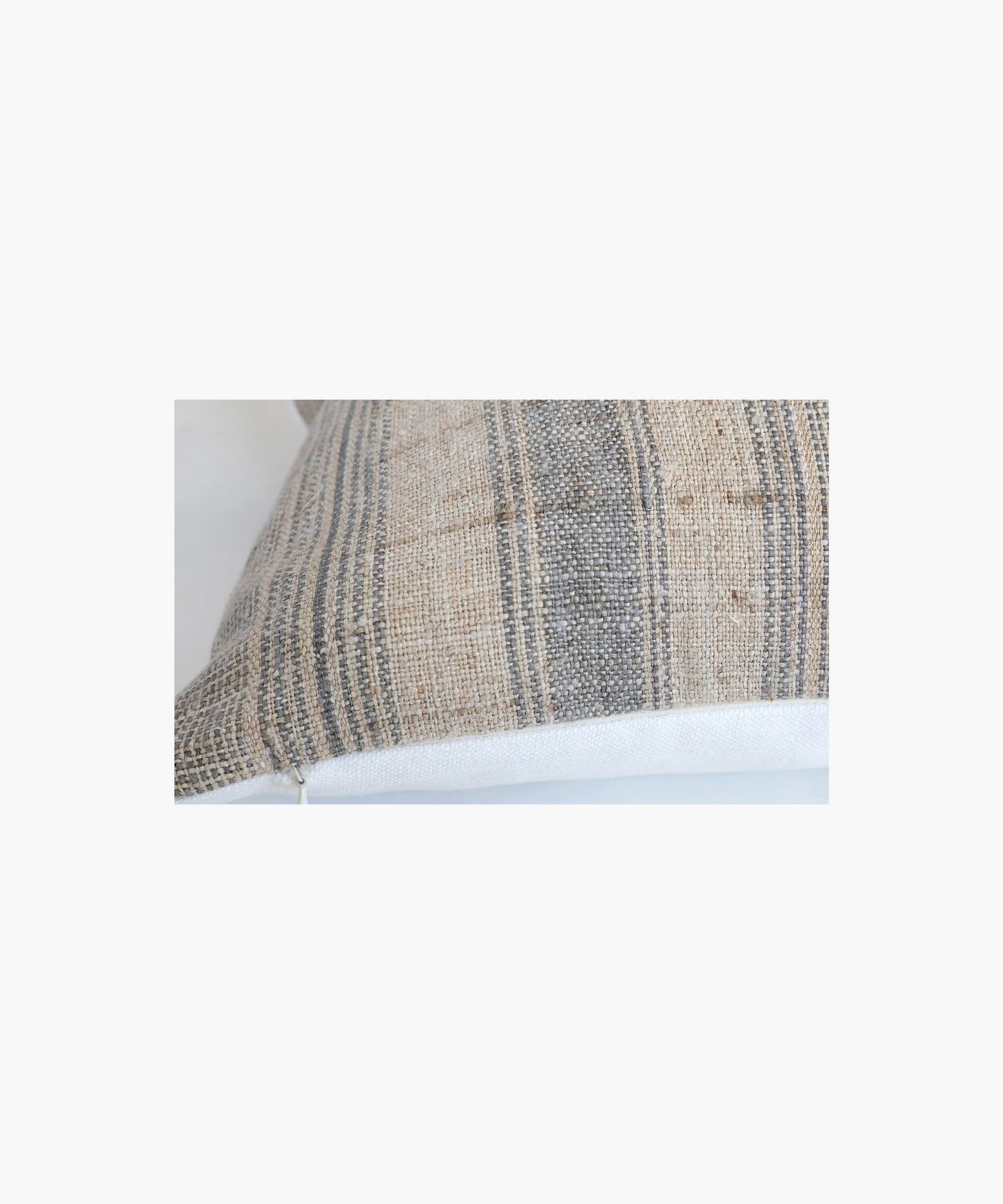 A close up of a pillow cover with a neutral hemp background features vertical grey and blue stripes. The texture appears soft and slightly textured, conveying a cozy and rustic feel.