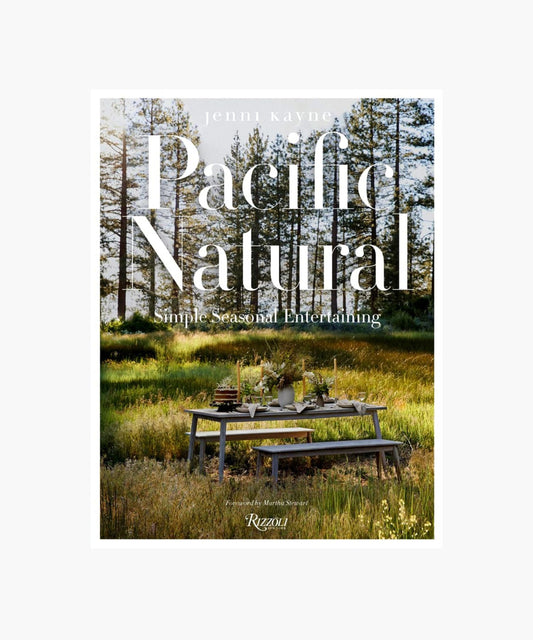 The cover of the book "Pacific Natural" by Jenni Kayne featuring a serene outdoor picnic scene with a rustic table set in a sunlit forest, conveying tranquility and elegance.