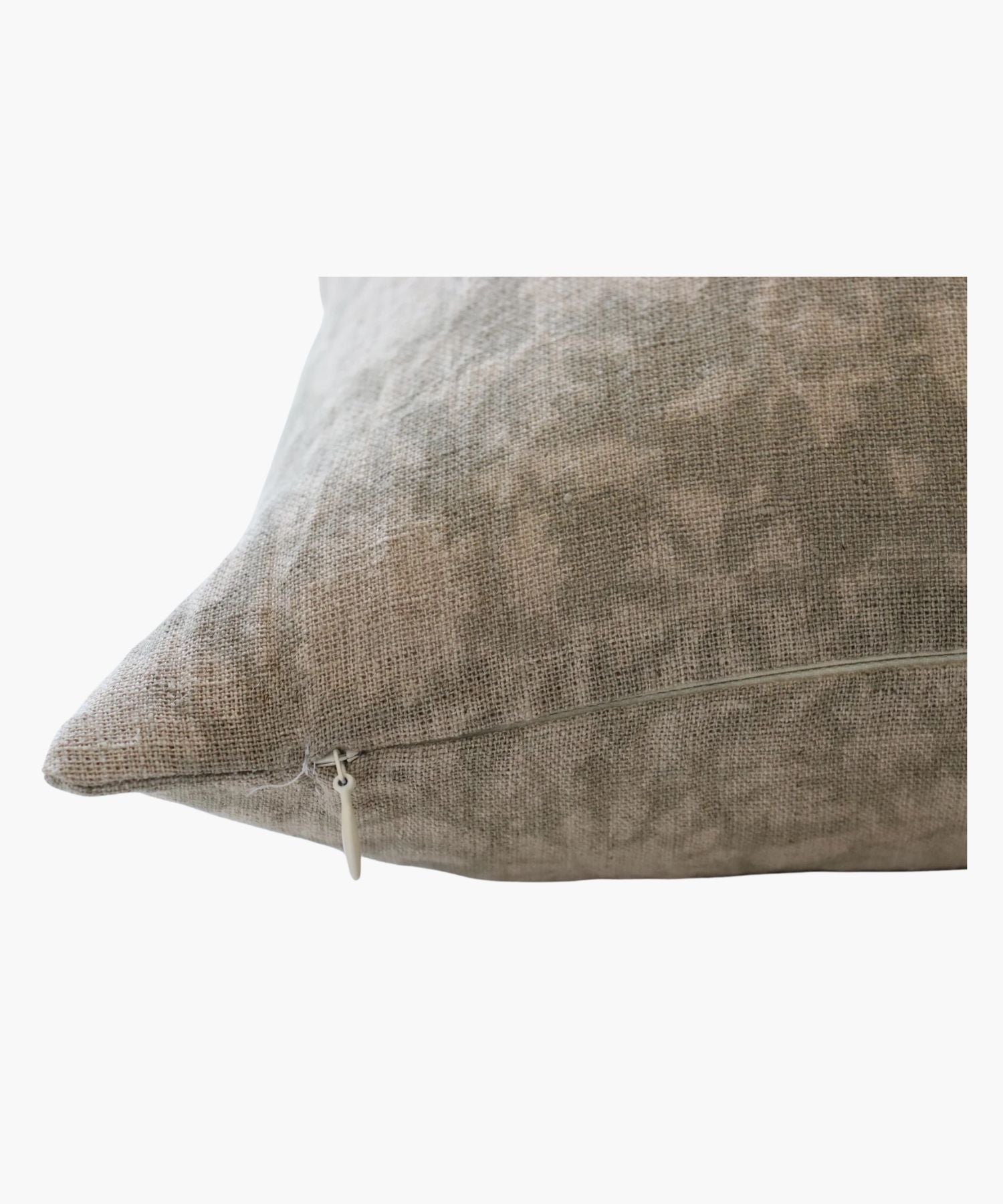 A close up of a pillow with a subtle floral pattern in soft grey tones on a natural linen fabric. The design is delicate, creating a cozy and elegant feel.