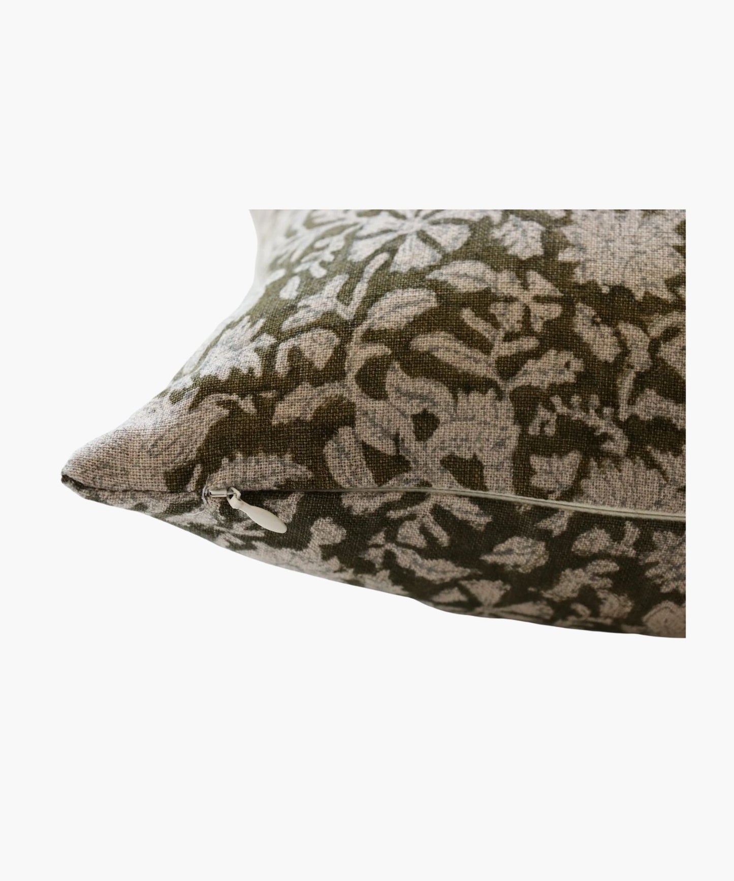 A close up of a pillow cover with an intricate floral pattern in white on an olive green background. The design conveys a natural and elegant feel.