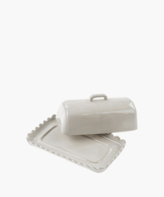 White ceramic butter dish with a lifted lid revealing a scalloped edge base. The glossy finish and simple design convey elegance and functionality.