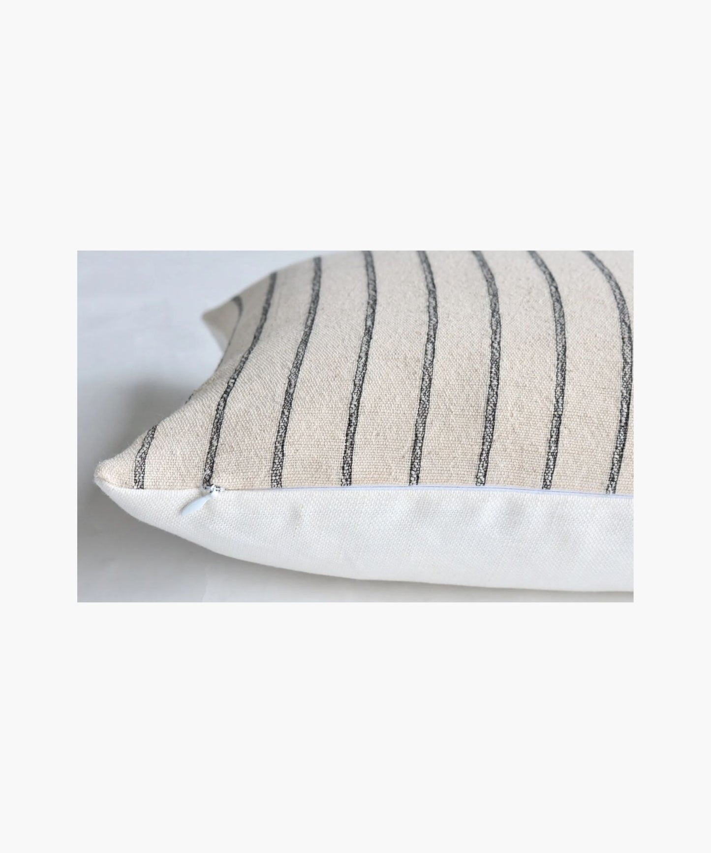 A close up picture of a pillow cover with vertical black  woven stripes on a cream background. The pattern is simple and elegant, conveying a calm and cozy atmosphere.