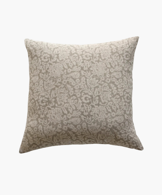 A beige square pillow with a light gray, intricate floral pattern. The design is elegant, adding a soft, decorative touch suitable for a cozy setting.