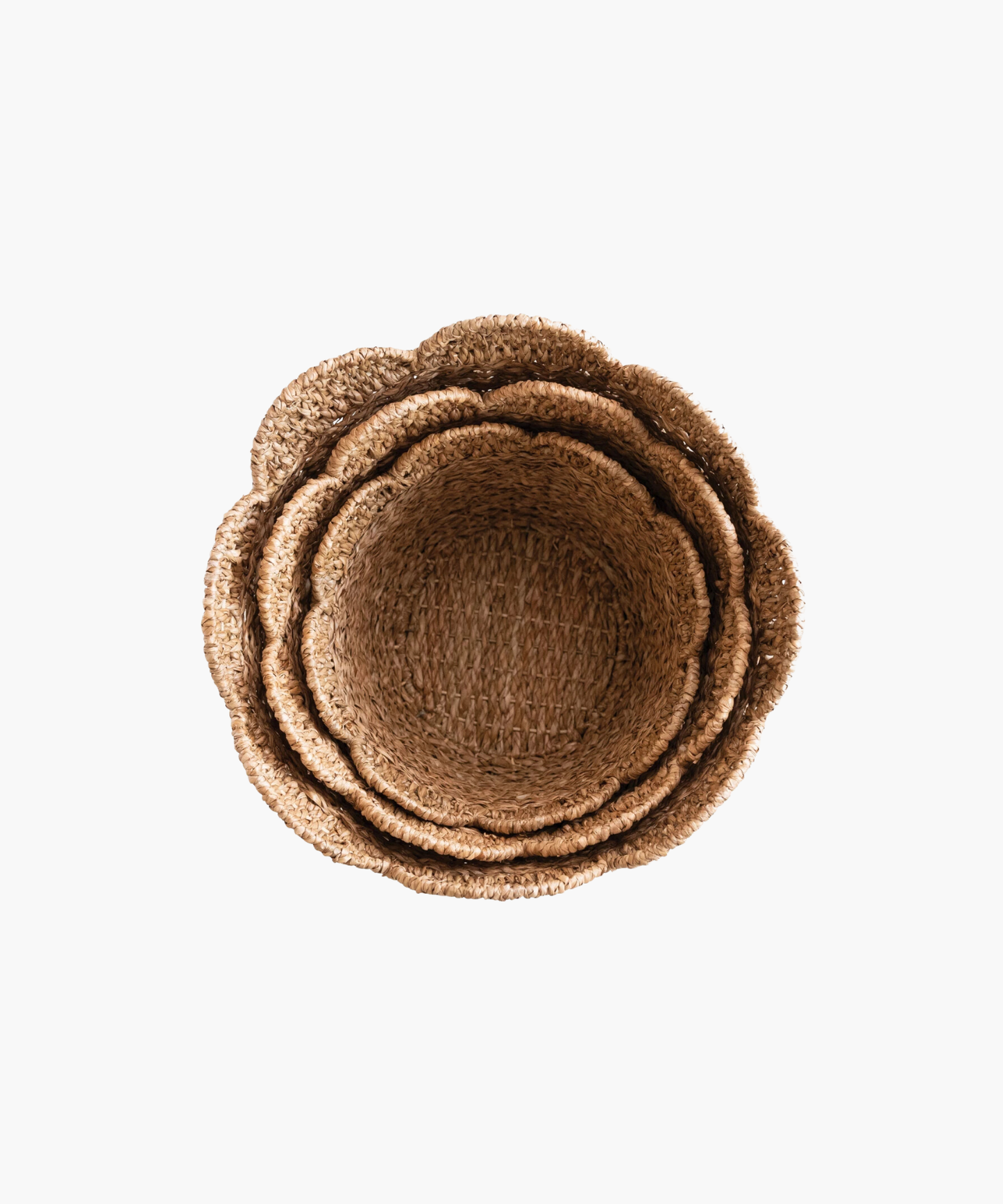 Overhead view of woven baskets in various sizes showing their scalloped edge in natural straw color. The texture is coarse, conveying a rustic and earthy tone.