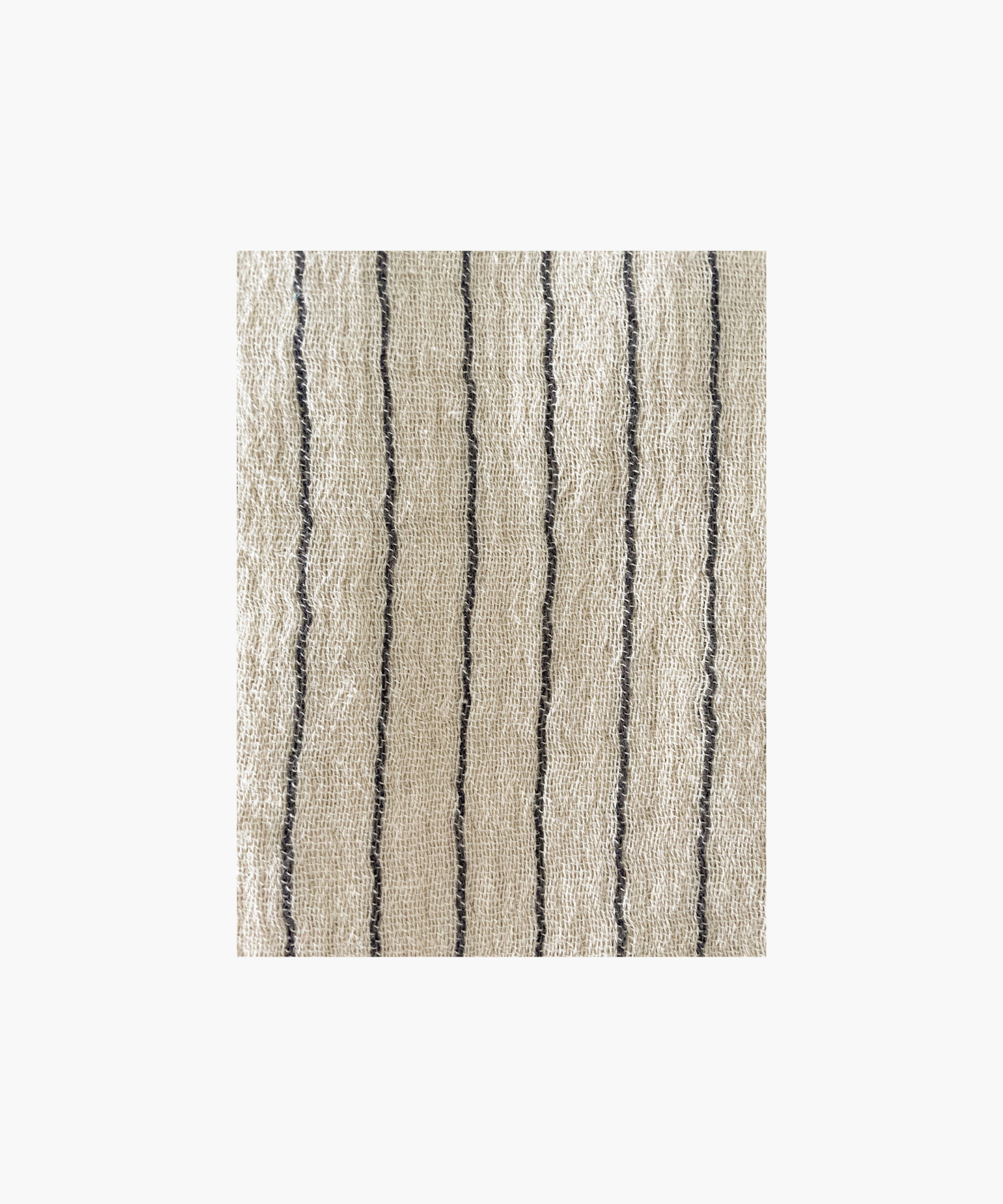 Close up of a beige throw blanket with thin black stripes. Highlighting the textured and soft fabric, evoking a sense of warmth and comfort.