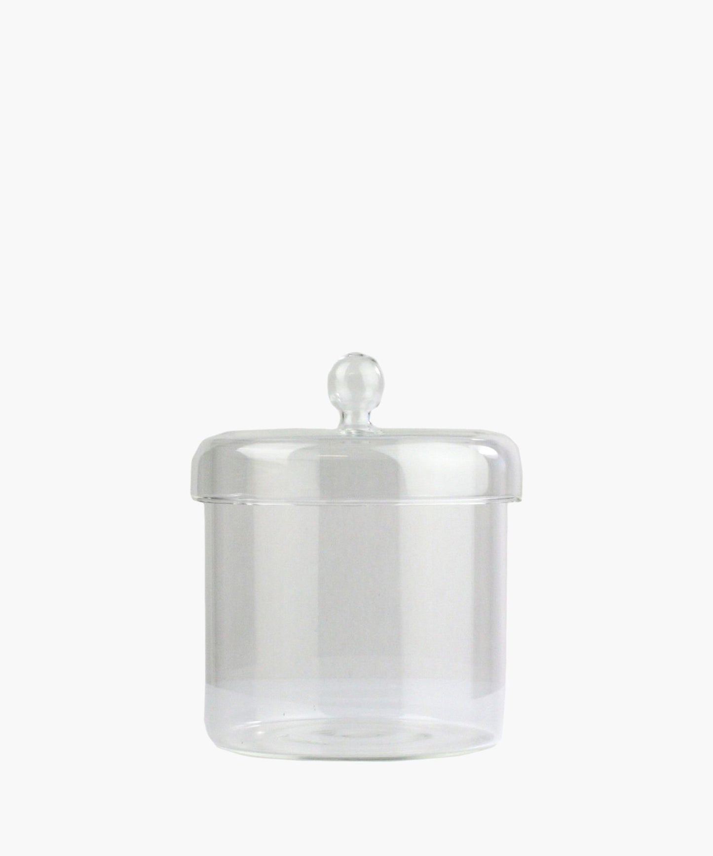 A clear glass jar with a round lid and a knob handle is centered on a plain white background. The jar is empty, conveying simplicity and elegance.