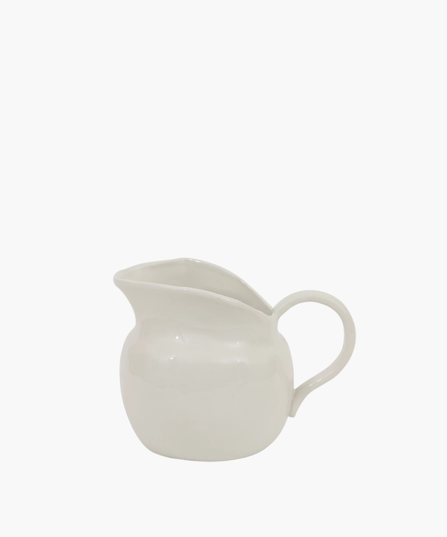 White ceramic pitcher with a round base and a wide spout, featuring a smooth surface and a curved handle. The mood is minimalistic and elegant.
